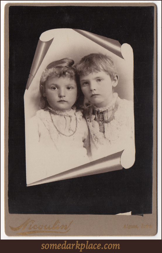 A trompe l'oeil image of two young children; one boy, one girl. Both are wearing white and have necklaces.