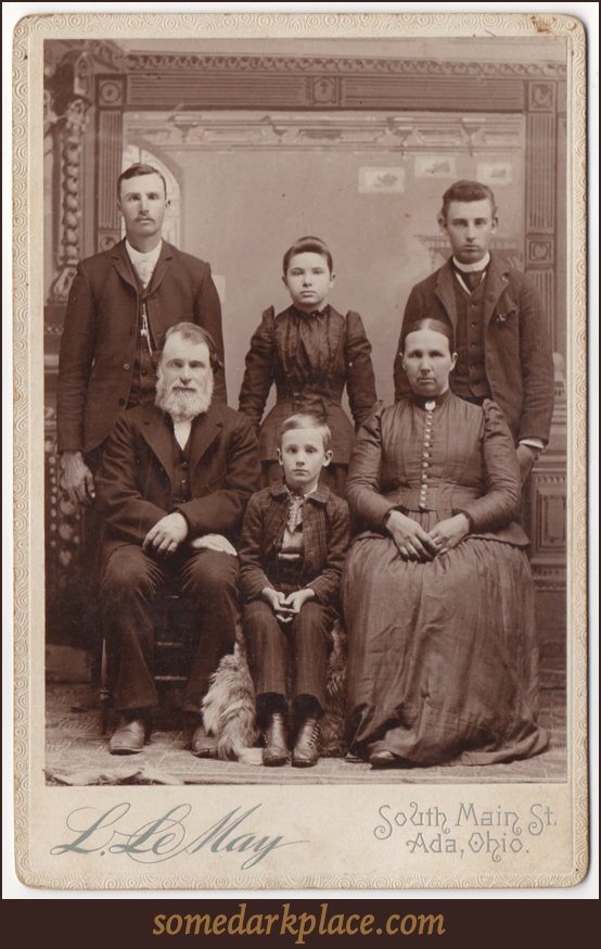 Presumably a family portrait. There are six subjects; three standing, three seated. There are four males and two females. Three adults are male, one female. All are wearing formal clothes.