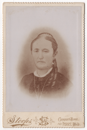 A bust of an older woman in a darker button dress or blouse. Her dress has lace ruff at the collar and she is wearing a large chain necklace (much of which cannot be seen). There appears to be some sort of bow or larger collar as well.